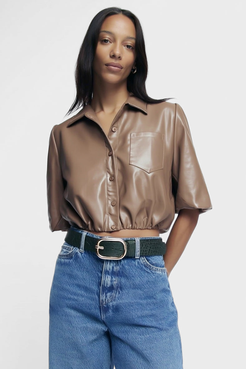 Woman wearing a brown leather shirt and blue jeans on a white background