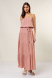 Woman wearing a pink strapless dress with a tiered skirt on a white background