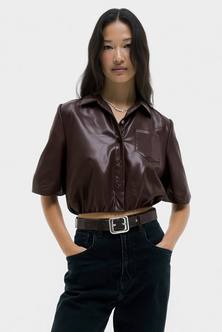 Woman wearing a brown leather shirt and black pants on a white background