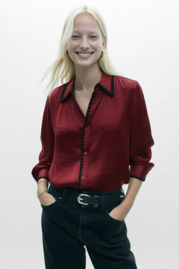 Person wearing a red shirt with black trim and black pants on a white background